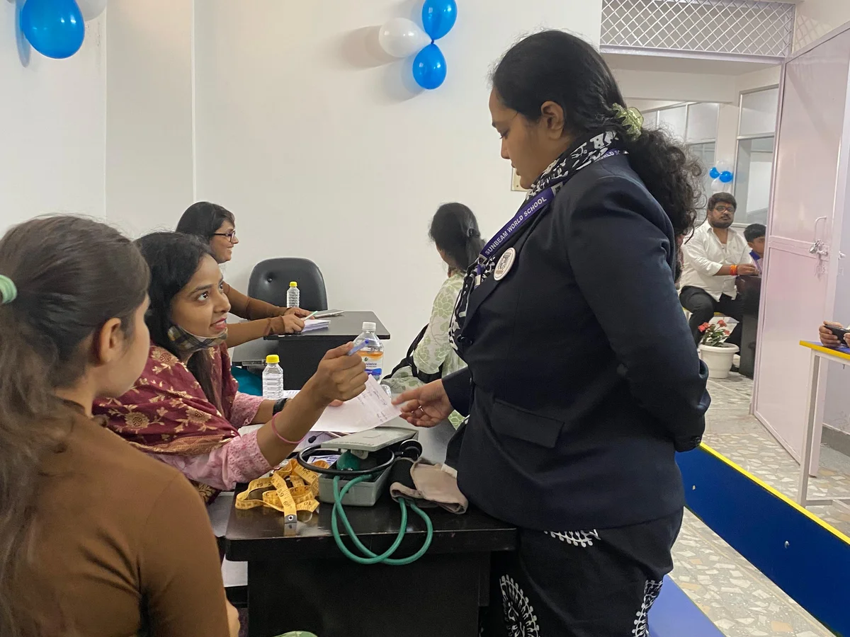 Staff supporting parents and students at a school health check-up camp at Sunbeam World School, Varanasi