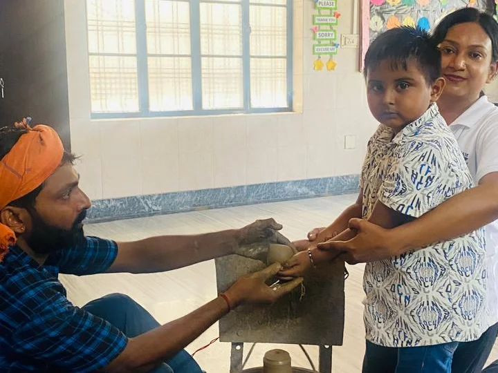 Staff supporting a student during a pottery activity at Sunbeam World School, Varanasi